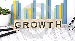 GROWTH word written on the wood block with chart, glasses and pencils