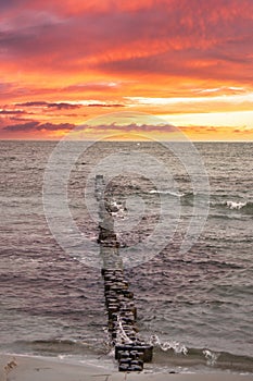 Groynes jut out into the Baltic Sea. Sunset on the horizon. Wooden logs protecting