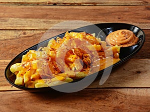 Grubby French fries served in a plate over a rustic wooden background, selective focus