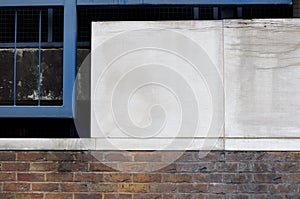 Grubby panelling above brick wall with metal frame to the side