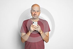 Grumpy bald man holding smartphone