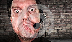 Grumpy Businessman with Frown Wearing Phone Headset In Office with Brick Background