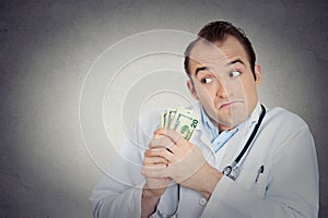 Grumpy greedy miserly health care professional holding money
