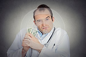 Grumpy greedy miserly health care professional holding money