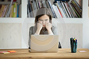 Grumpy not amused office worker looking at laptop screen.