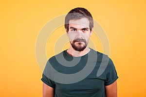 Grumpy stressed worried man on yellow background lookin at the camera