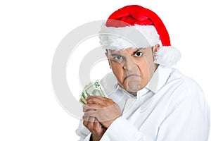 Grumpy young man in santa's hat possessive about his money photo