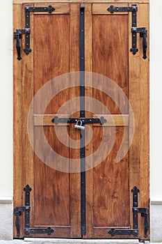 Grunge brown wooden door with forged hinges. Vintage door locked with a padlock.