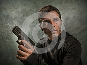 Grunge cinematic portrait of attractive and dangerous looking hitman or secret service especial agent man in action pointing gun