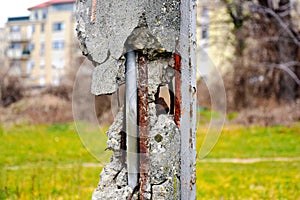 grunge cracked concrete column with exposed rusty steel reinforcing bars. soft blurred background