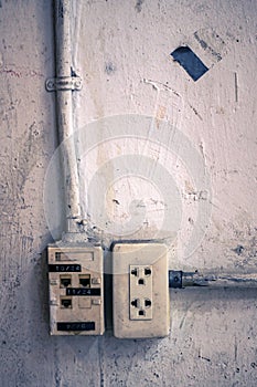 A grunge electric and network plug on the aged white wall with color toned
