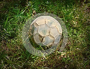 Grunge football or soccer ball on a green lawn