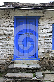 Grunge gray bricks wall with blue door of Nepali house.