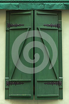 Grunge green wooden shutters with forged hinges.