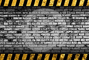 Grunge grey brick wall background with warning stripes