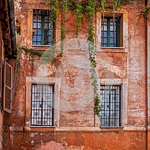 A grunge house orange wall and four windows in Trastevere historic neighborhood.