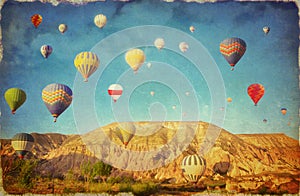 Grunge image of colorful hot air balloons against blue sky in C