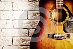 Grunge image of the old acoustic guitar in the interior with white brick wall