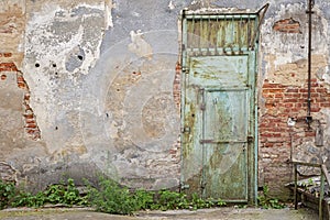 Grunge metal door, cracked red brick wall