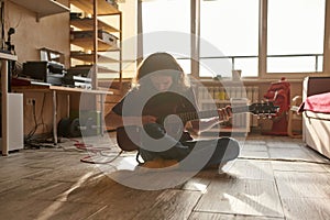 Grunge musician playing electric guitar at home