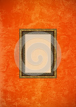 Grunge orange stucco wall with empty picture frame