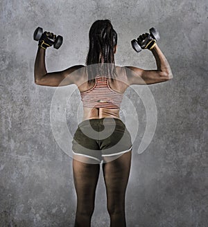 Grunge sport advertising style portrait of young athletic woman with strong back and fit body holding dumbbells in fitness trainin