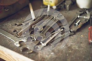 Grunge, vintage wooden workbench with rustic old metal wrenches of different measures lying. Old toolbox background. View from top