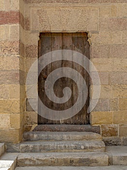 Grunge wooden aged door on exterior stone bricks wall