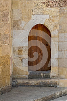 Grunge wooden aged vaulted door on exterior stone bricks wall