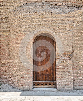 Grunge wooden aged vaulted door on stone bricks wall