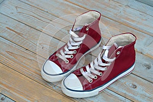 Grunge wooden background with red and white used vintage canvas sneakers