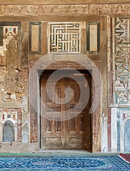 Grunge wooden decorated door on external old decorated marble wall, Cairo, Egypt