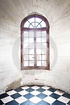 Grungy arched window inside old building.