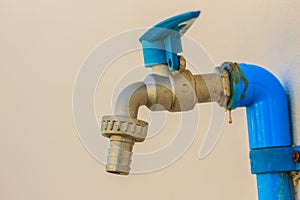 Grungy bronze field faucet connected with blue PVC pipe in white