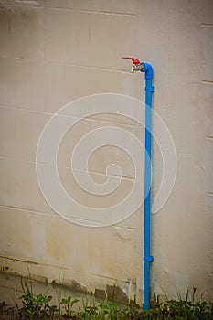 Grungy bronze field faucet connected with blue PVC pipe in white