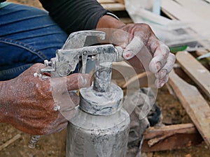 A grungy dirty paint sprayer in hands of a painter about to be opened and refilled to get it ready for the next round of spraying