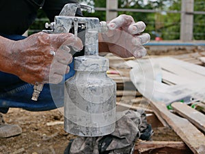 A grungy dirty paint sprayer in hands of a painter about to be opened and refilled to get it ready for the next round of spraying