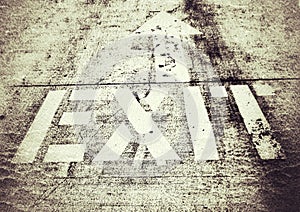 Grungy Exit Sign and Arrow Painted on Concrete Pavement