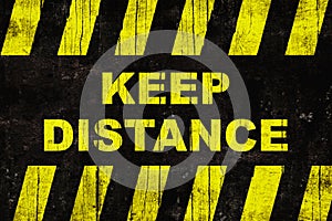 Keep distance text as warning sign with yellow and black stripes on painted wooden wall