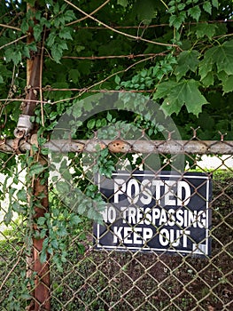 Grungy No Trespassing Sign on Rusty Chain Link Fence.