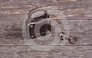 Grungy steel metal key and rusted lock on a old wooden boards background