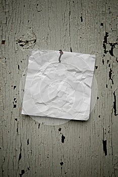 Grungy torn note paper nailed on rustic old weathered background