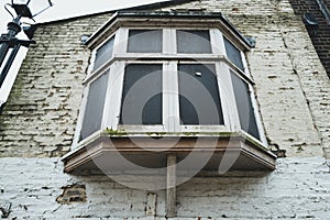 Grungy view of a boarded up bay window shown on a derelict town home.