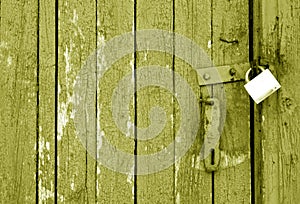 Grungy wooden door with lock in yellow tone