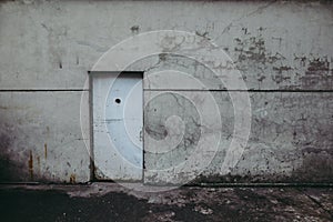 Grungy worn out metallic door in the wall of an old prison of the communist Romanian Securitate