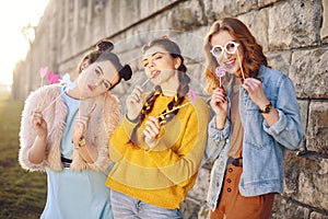 Grup of three girls with funny lips, glasses, stars, paper hearts on stick at the sunset having fun. Going crazy, smile at summer