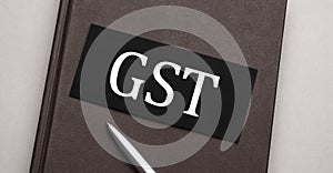 GST GOODS AND SERVICES TAX sign written on the black sticker on the brown notepad. Tax concept