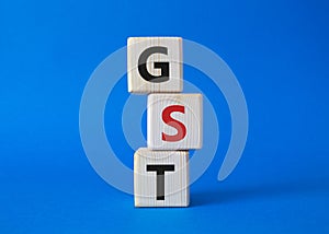 GST - Goods and Services Tax symbol. Concept word GST on wooden cubes. Beautiful blue background. Business and GST concept. Copy