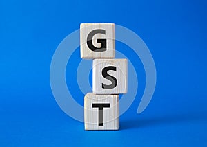 GST - Goods and Services Tax symbol. Concept word GST on wooden cubes. Beautiful blue background. Business and GST concept. Copy