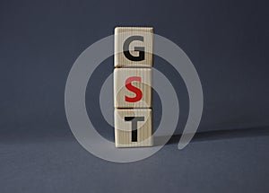 GST - Goods and Services Tax symbol. Concept word GST on wooden cubes. Beautiful grey background. Business and GST concept. Copy